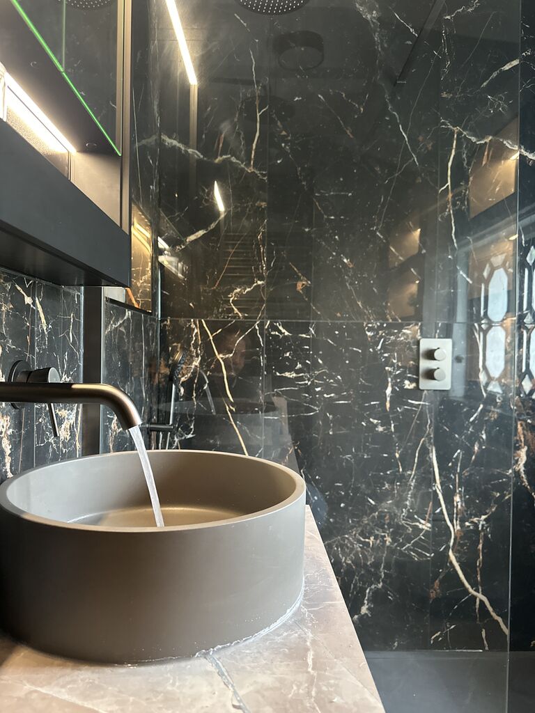 Concrete-grey vessel basin with fluted gunmetal wall-mounted tap running Gosfield CO9 Essex