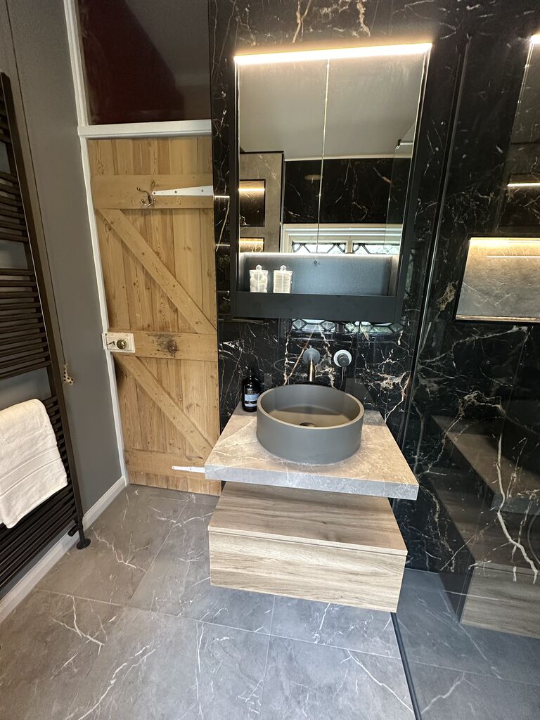 Oak-effect vanity with concrete vessel basin and backlit mirror cabinet in black marble shower room Gosfield CO9 Essex