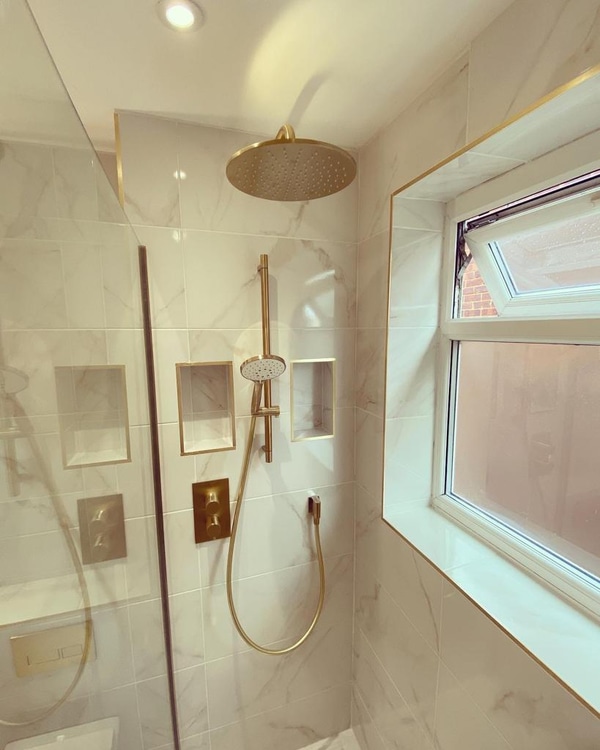 Brushed brass rainfall shower with twin brass-framed niches in a Great Baddow CM2 family bathroom