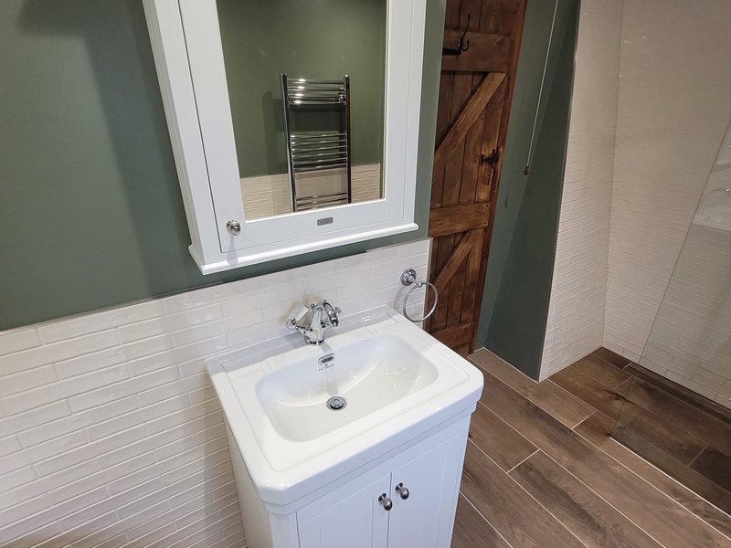White vanity unit with mirrored cabinet chrome towel ring and rustic oak door Great Bardfield CM6