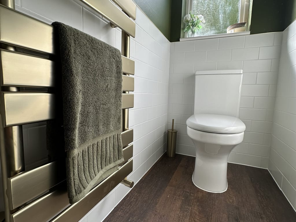 JTP Hix brushed brass radiator with olive green towel beside Charlotte back-to-wall WC Great Leighs CM3
