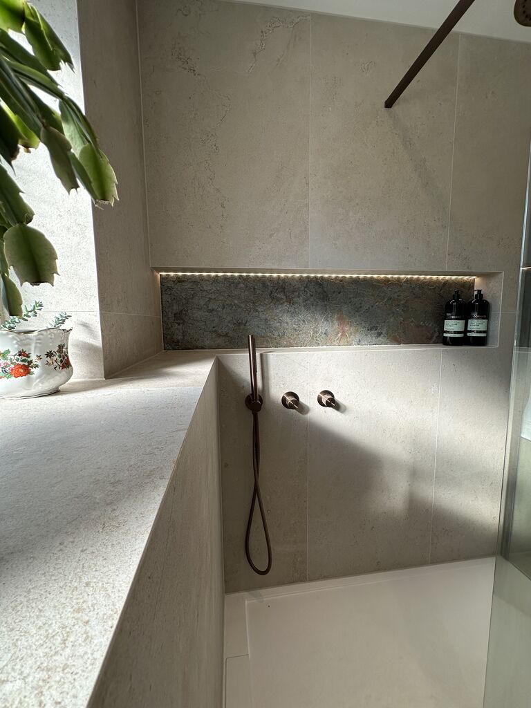 LED-lit niche above the tiled half-wall with JTP bronze hand shower Great Notley CM77 Essex
