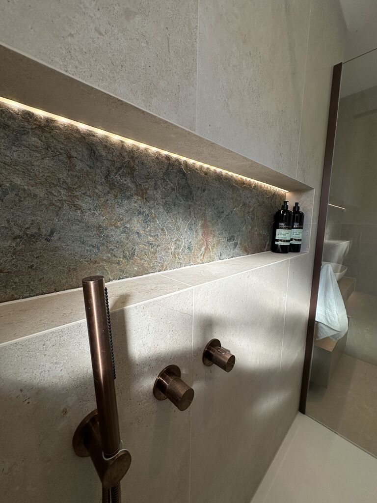 Full-width LED-lit shower niche with copper slate back and JTP brushed bronze hand shower Great Notley CM77 Essex
