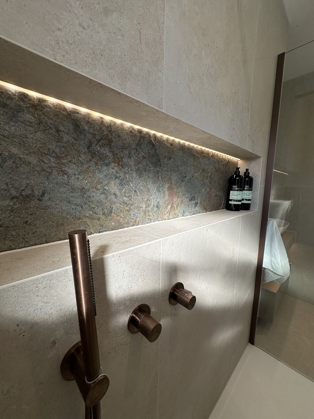 Full-width LED-lit shower niche with copper slate back and JTP brushed bronze hand shower Great Notley CM77 Essex