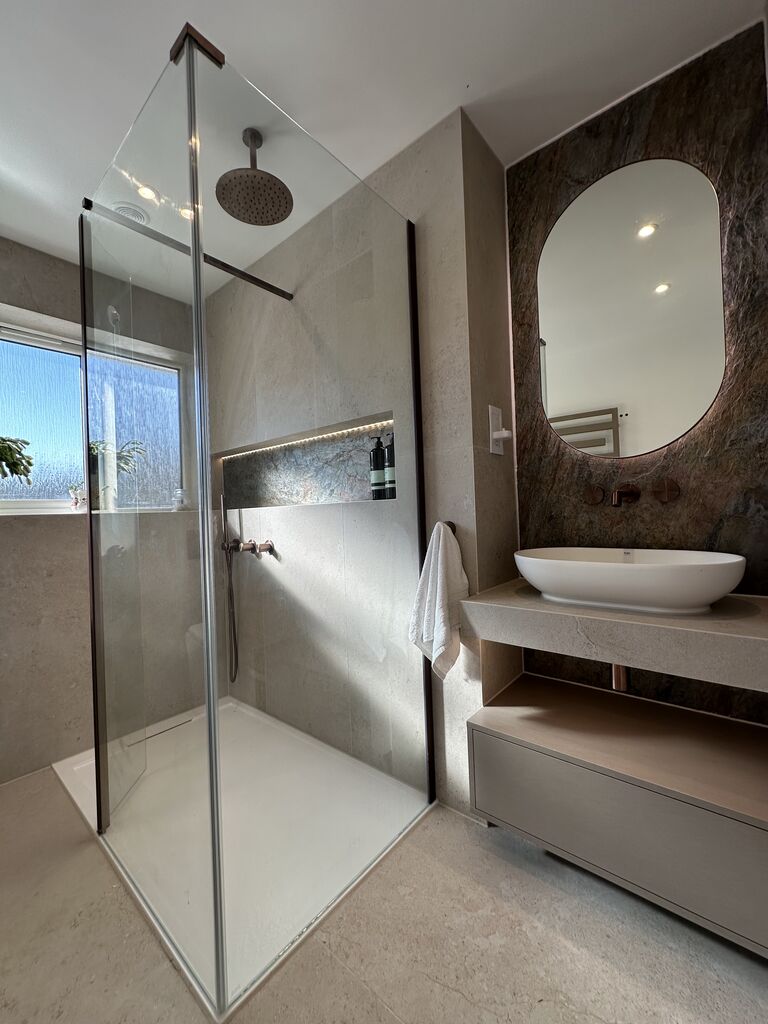Walk-in shower with bronze rain head and glass screen beside floating vanity Great Notley CM77 Essex