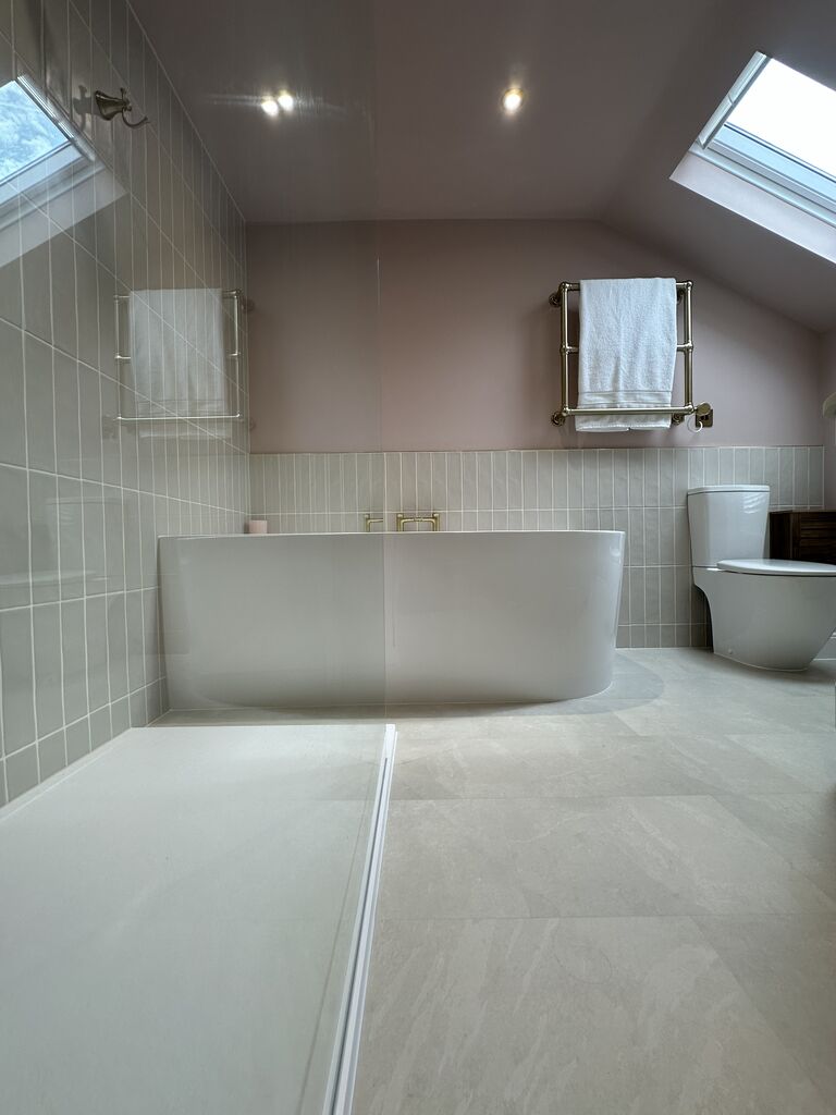 D-shaped bath under skylights with blush pink walls and brass towel warmer Great Waltham CM3 Essex