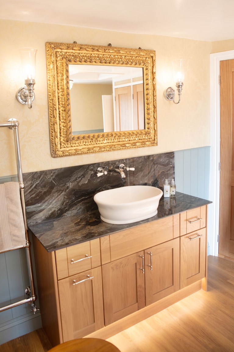Calypso oak vanity with granite worktop and backsplash, BC Designs vessel basin, gold mirror and Burlington wall lights Halstead CO9