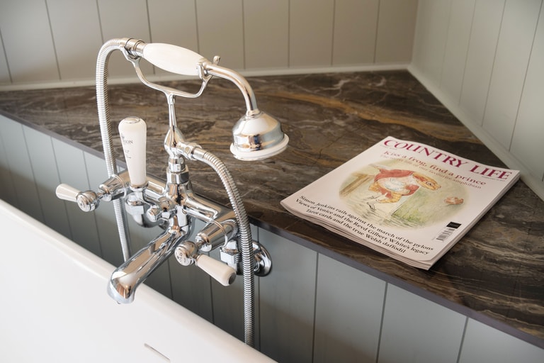 Chrome bath tap and shower mixer on granite surface with Country Life magazine beside Brampton bath Halstead CO9