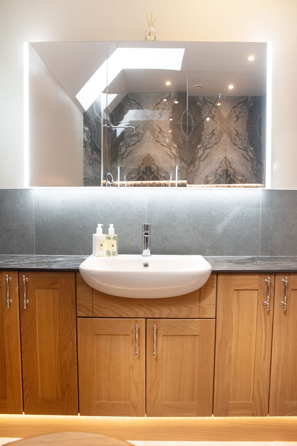 Calypso oak vanity with semi-recessed basin and LED-edged mirror cabinet reflecting bookmatched tiles Halstead CO9