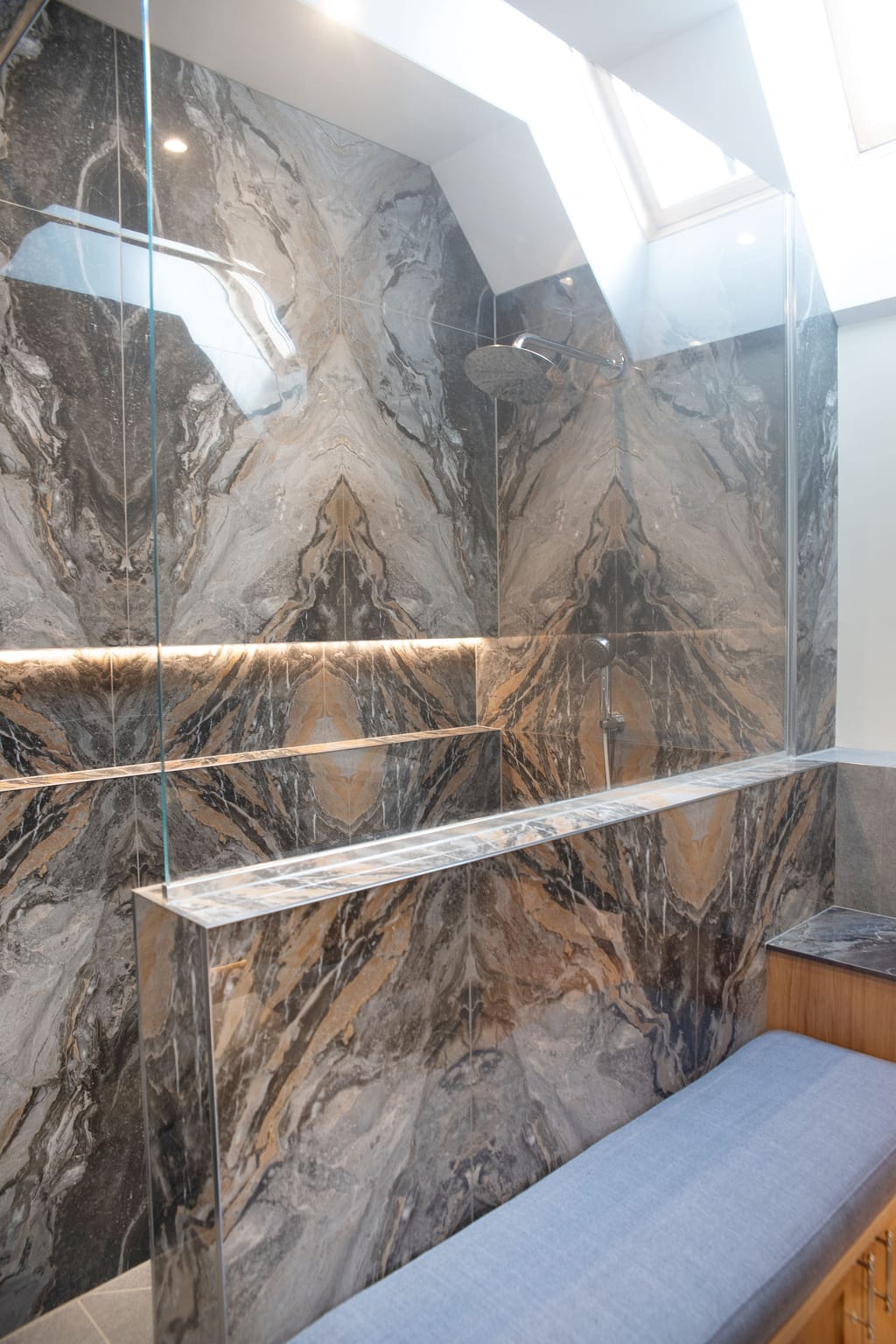 Half-height tiled wall with frameless glass panel, bookmatched feature wall and oak bench Halstead CO9