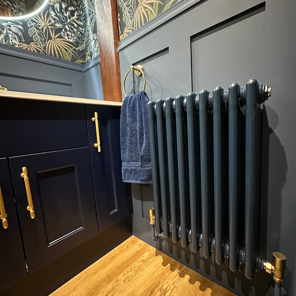 Vogue UK column radiator in custom navy finish with JTP brushed brass towel ring on oak flooring Hatfield Peverel CM3