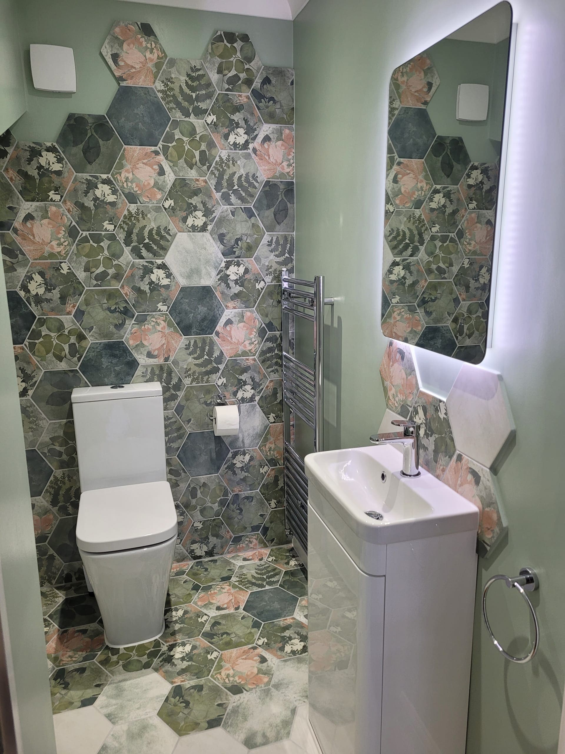 Pink and green botanical hexagon tiles with white sanitaryware in a Colchester cloakroom