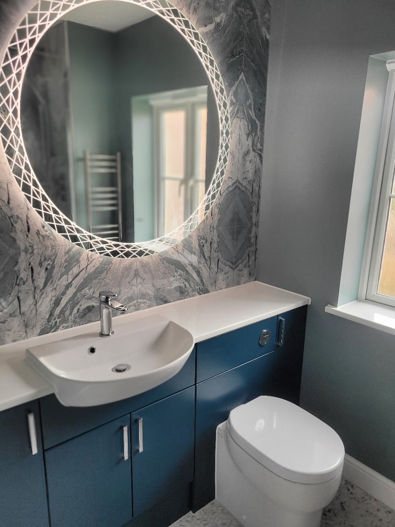 Roper Rhodes blue vanity with HiB Bellus crosshatch LED mirror and Ocean Magnifique bookmatched wall Highwoods CO4