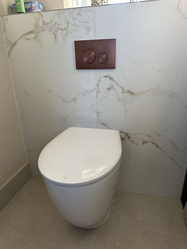 Back-to-wall WC with brushed bronze flush plate on marble-look panel Kelvedon CO5 Essex