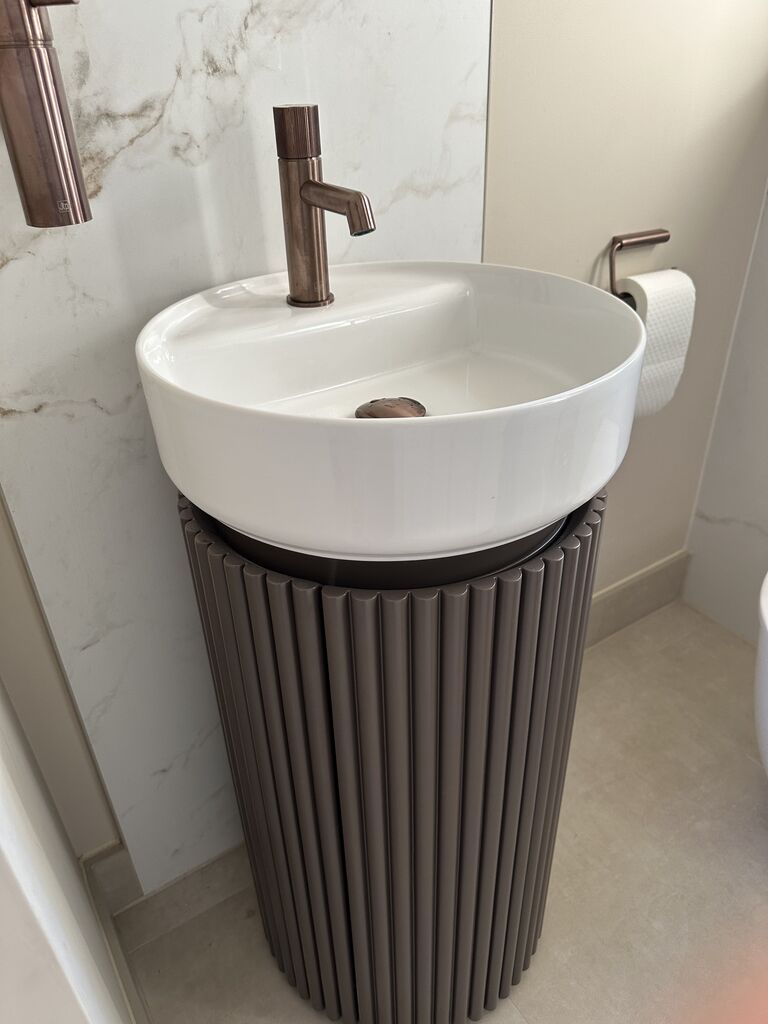 Fluted basin unit with round basin and brushed bronze tap against marble-look panel Kelvedon CO5 Essex