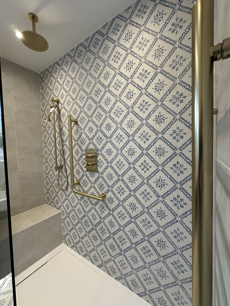 Ceiling-mounted brushed brass rain head above a blue patterned tile feature wall Kelvedon CO5 Essex