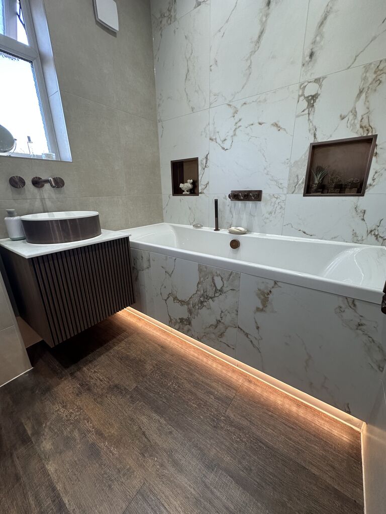 Fluted walnut vanity and LED-underlit bath with marble wall Kelvedon CO5 Essex family bathroom Bowman Bathrooms