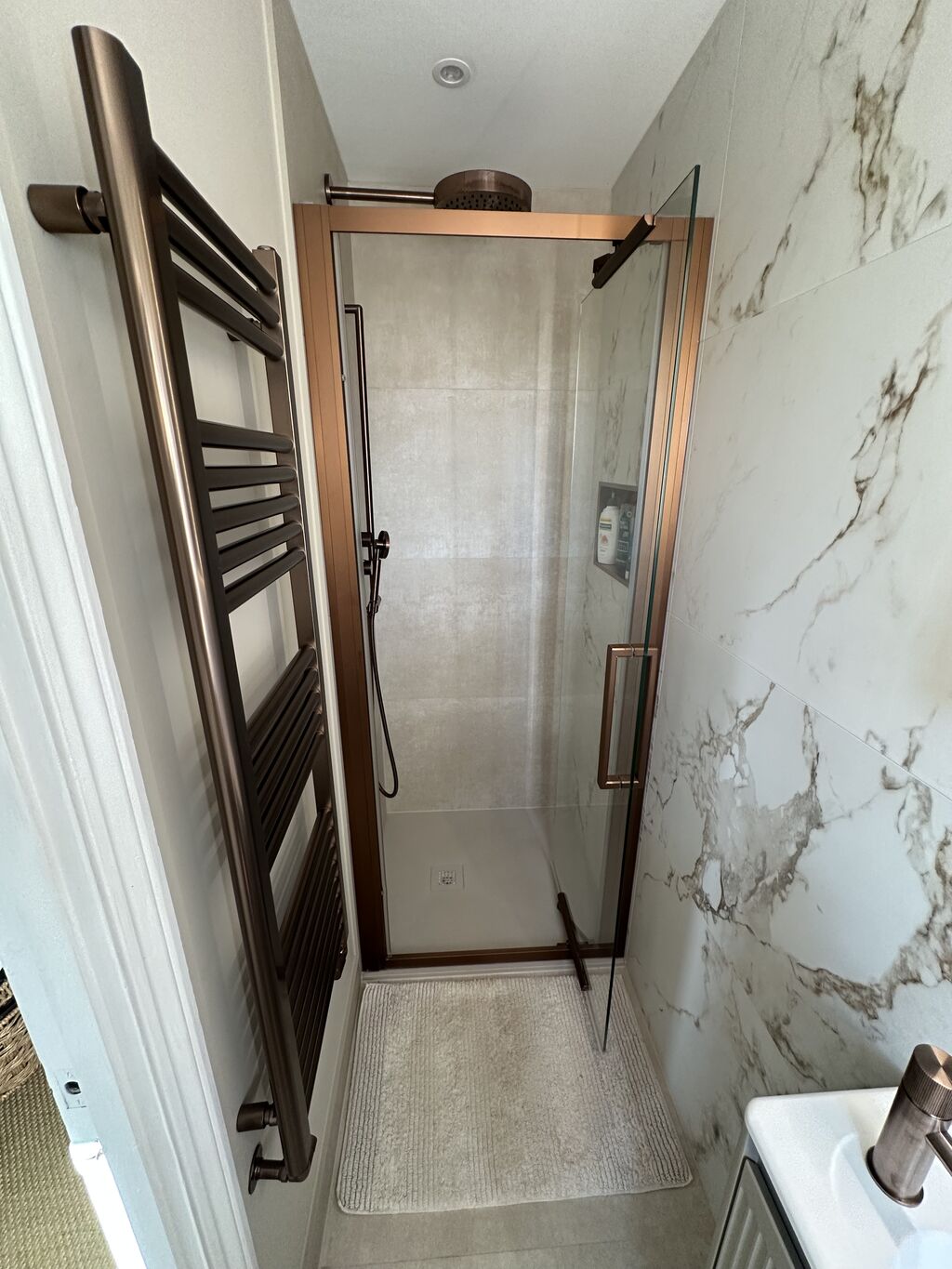 Bronze ladder towel rail beside marble-walled shower Kelvedon CO5 Essex ensuite