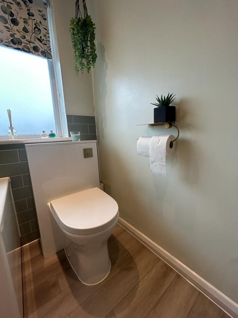 Back-to-wall WC with sage green tile splashback and Amtico wood-effect floor West Mersea CO5