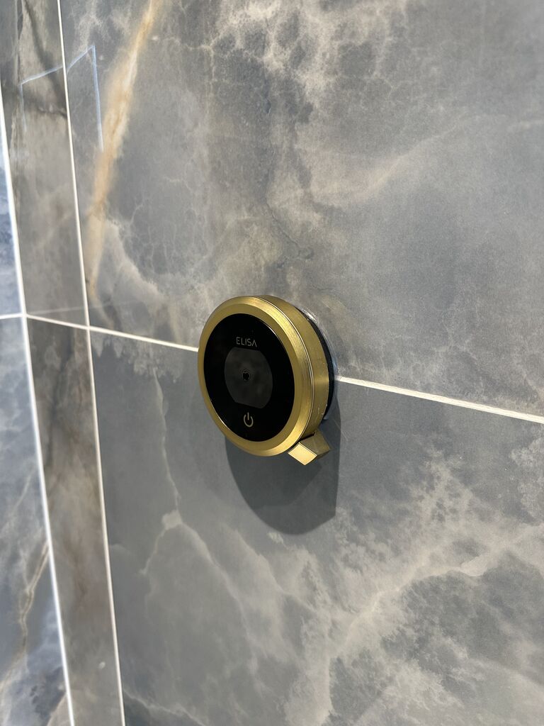 Brushed brass digital shower control set into marble-effect porcelain Wickham Bishops CM8 Essex