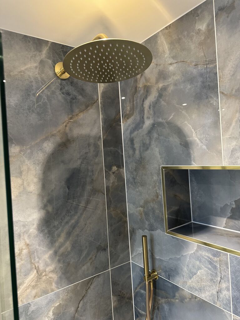 Brushed brass rain head and brass-framed shower niche on marble-effect porcelain Wickham Bishops CM8 Essex