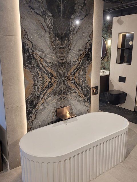 Fluted freestanding bath and book-matched marble feature wall on display inside the Bowmans Leigh-on-Sea showroom