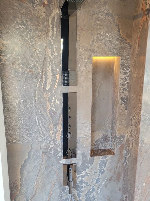 Walk-in wetroom shower setting with a recessed shower column and lit niche at the Leigh-on-Sea showroom